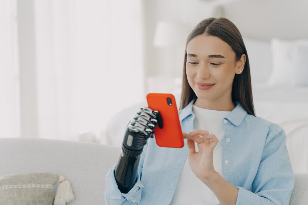 Happy european woman with bionic artificial arm chatting on smartphone. Innovation development.